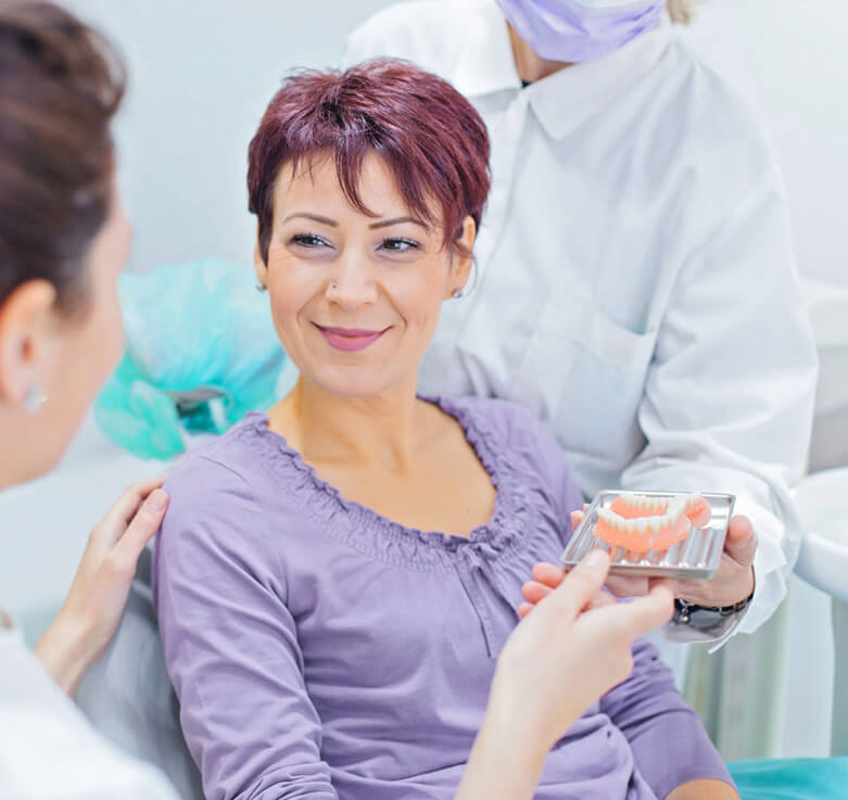 image of Female dentist talking to a patient and showing her teeth dentures